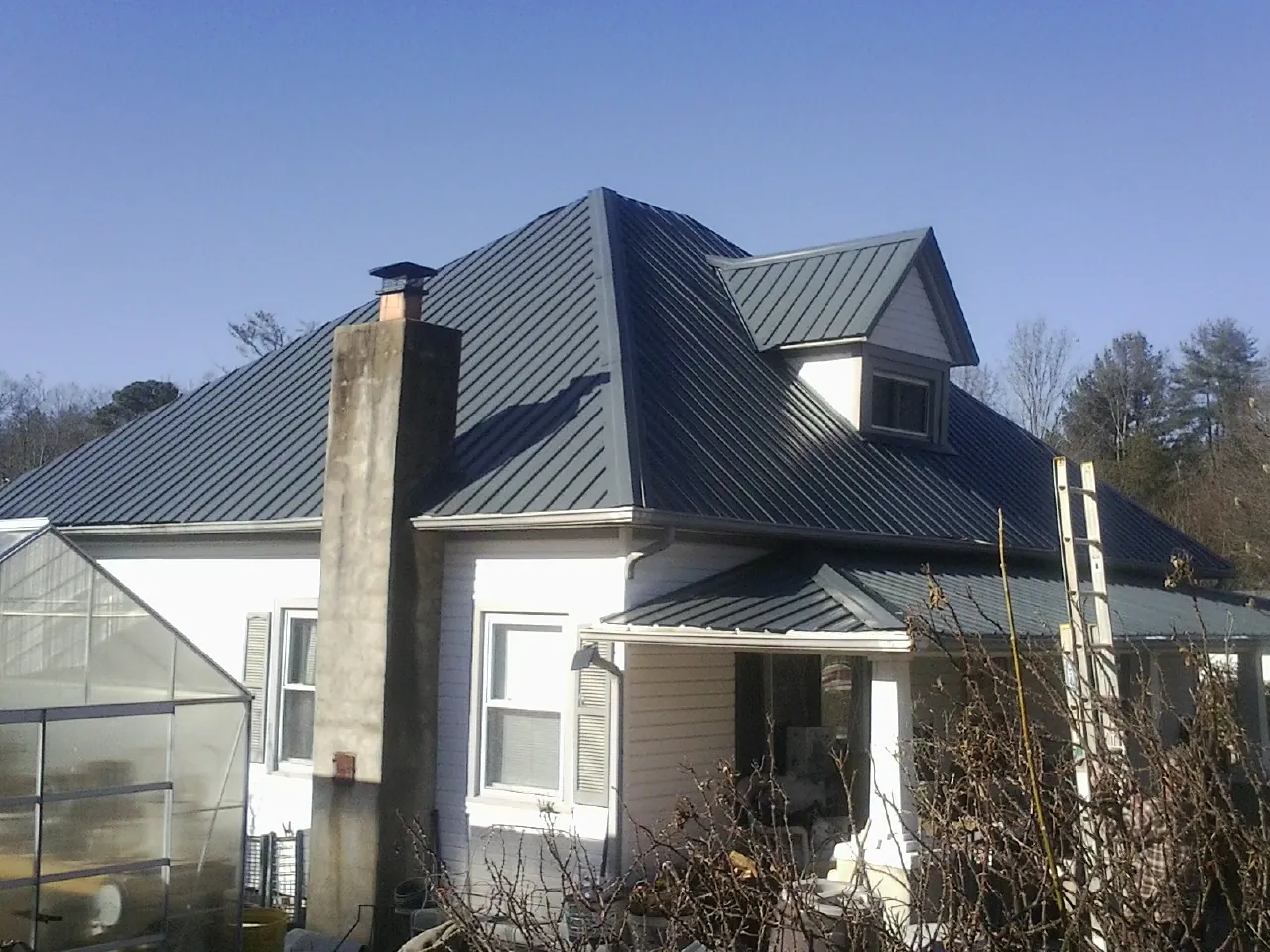 Dark blue standing seam metal roof on a white farmhouse with dormer — Slate & Tile Roof Repair by Roofing Brothers in Springboro
