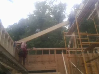 Carpenter raising a rafter beam on a new second story frame in Springboro