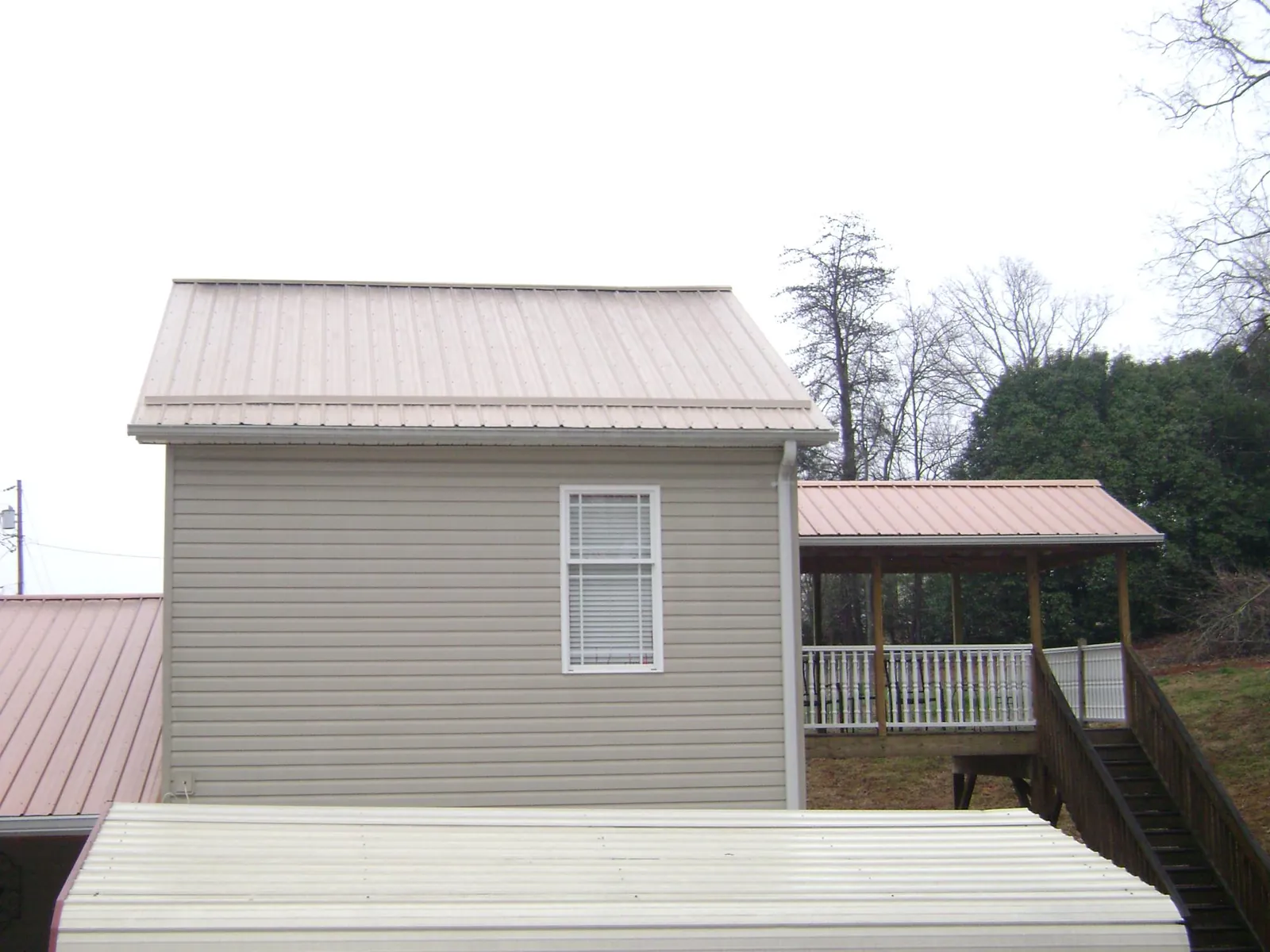 Tan metal roofs on a two story addition and attached porch, from a Roof Replacement job in Springboro