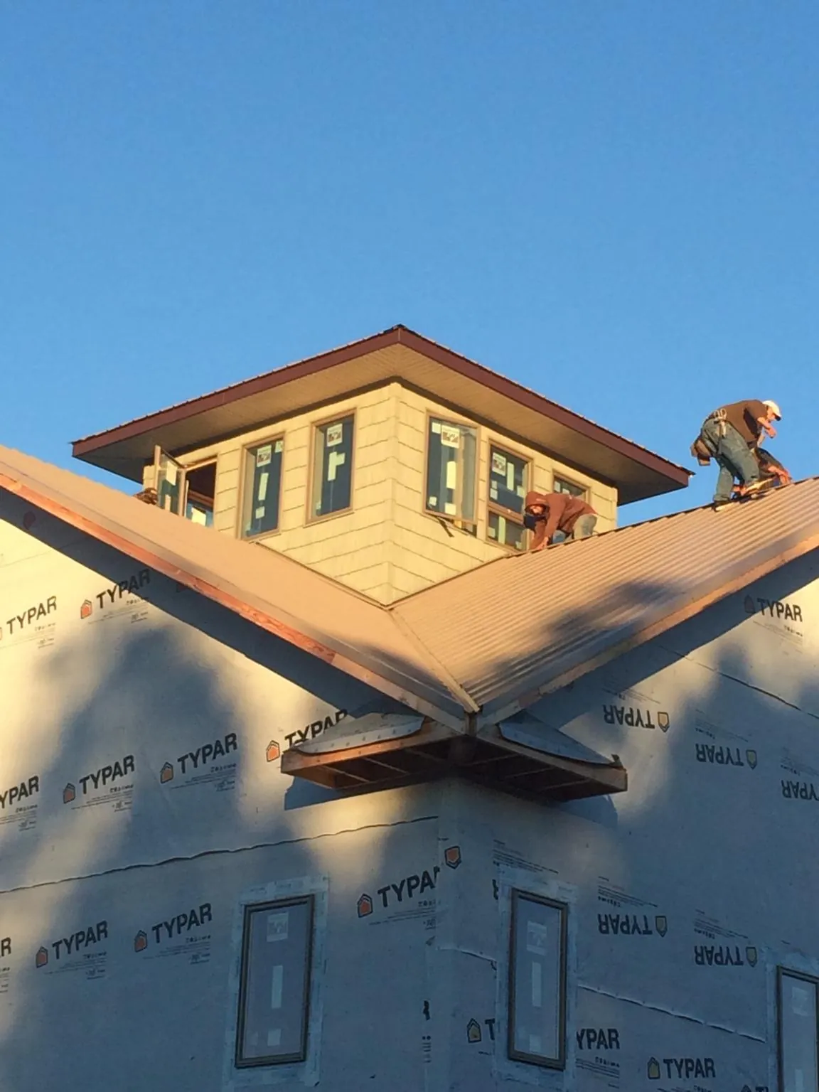 Roofers working around a rooftop cupola on a new metal roof at sunset — Roof Waterproofing in Springboro by Roofing Brothers